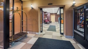 A hotel lobby with a checkered floor, a vending machine, a reception desk, and a view into a room.