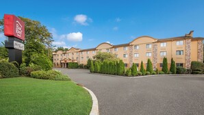 A hotel with a paved driveway leading to a building with multiple windows and a flat roof.