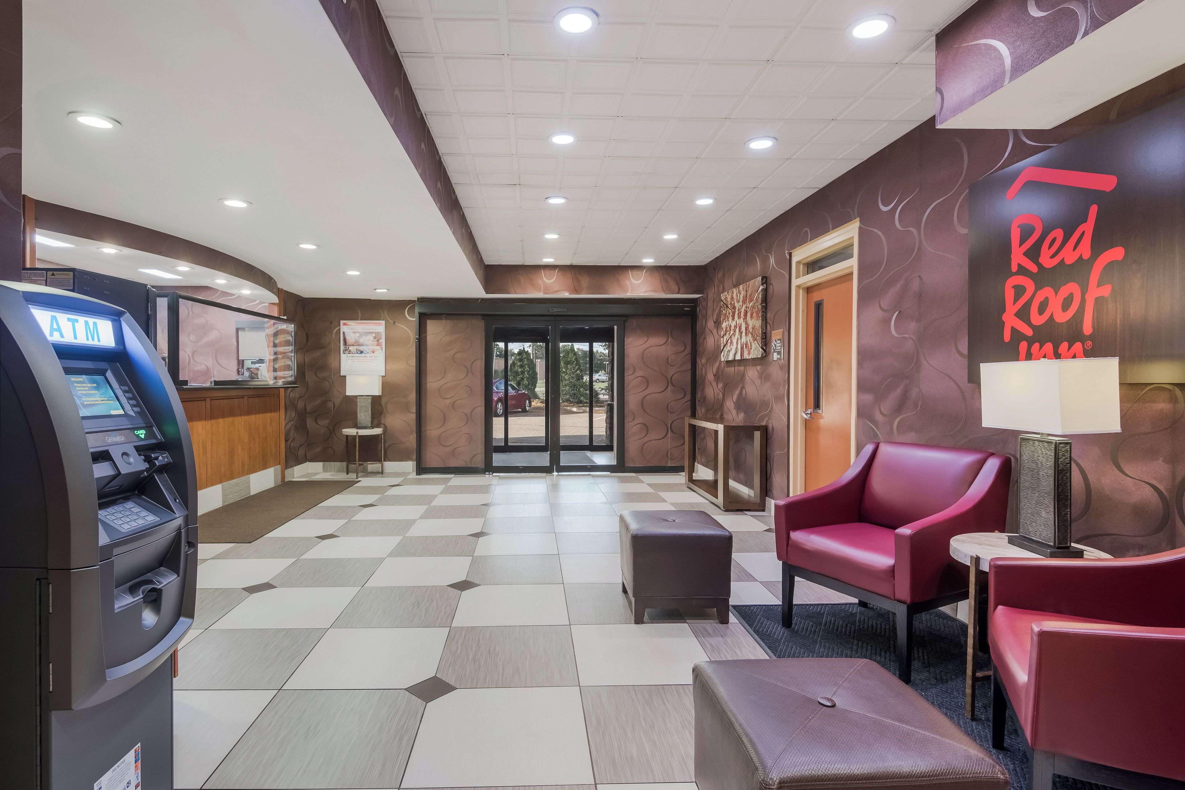 Vestíbulo de Red Roof Inn con un cajero automático, zona de estar y mostrador de recepción.