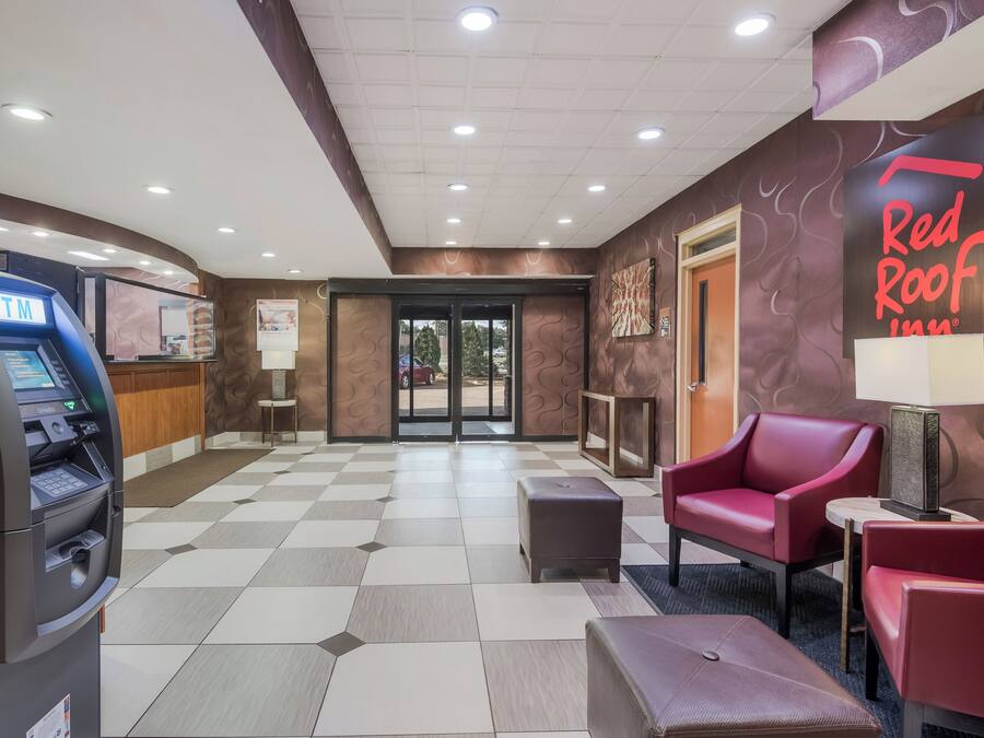 A Red Roof Inn lobby with an ATM, seating area, and a check-in counter.