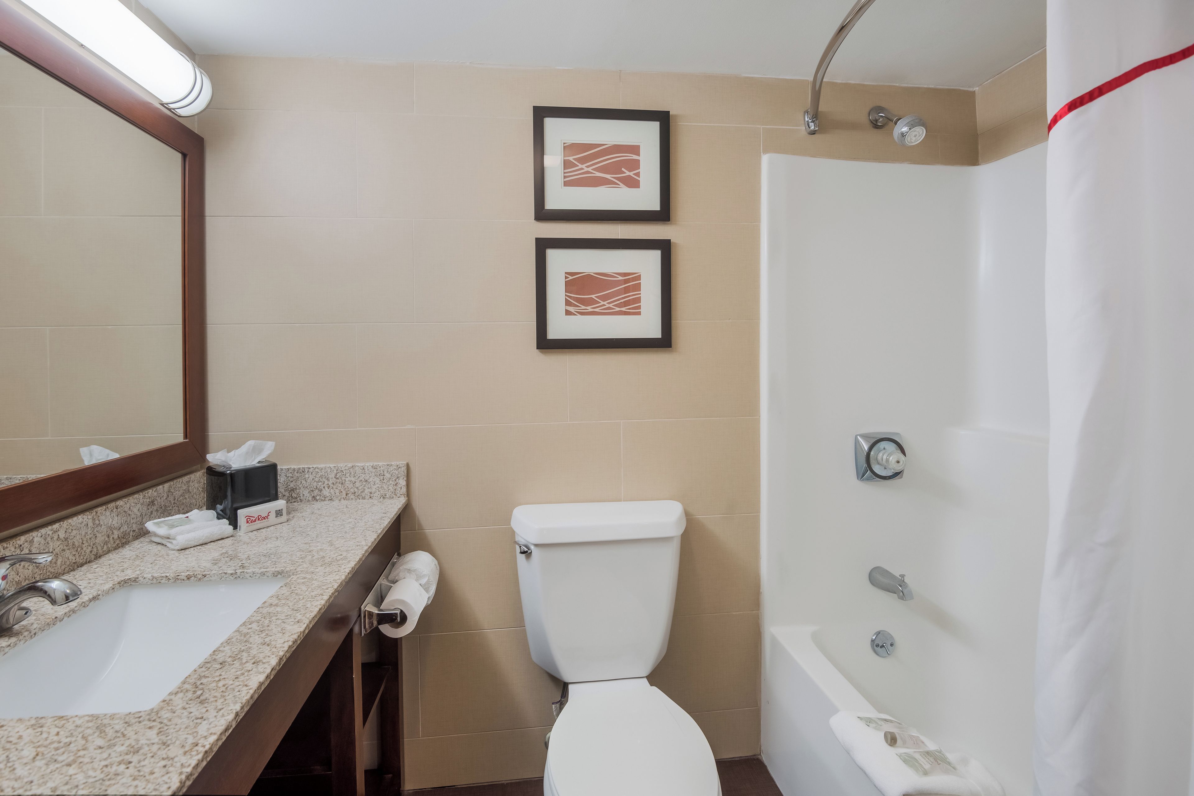 Une salle de bain avec un lavabo, des toilettes et une baignoire. Deux tableaux encadrés sont accrochés au mur.