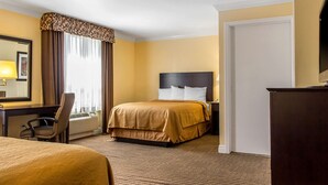 A hotel room with a large bed, a desk with a chair, a dresser, and a large mirror. - Quality Inn near Mountain Creek (Vernon)