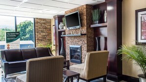 A lobby with a brick wall, a flat-screen TV, a fireplace, and seating areas. - Quality Inn near Mountain Creek (Vernon)