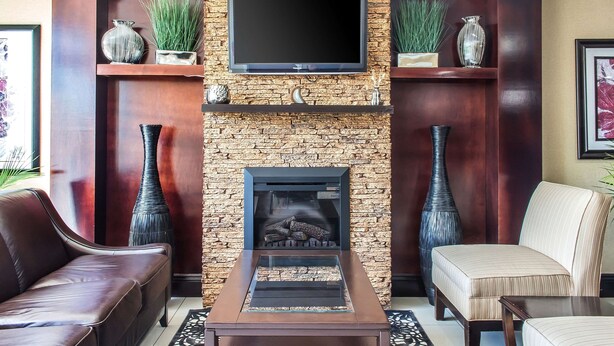 A modern living room with a stone fireplace, a flat-screen TV mounted above it, and two sofas. - Quality Inn near Mountain Creek (Vernon)