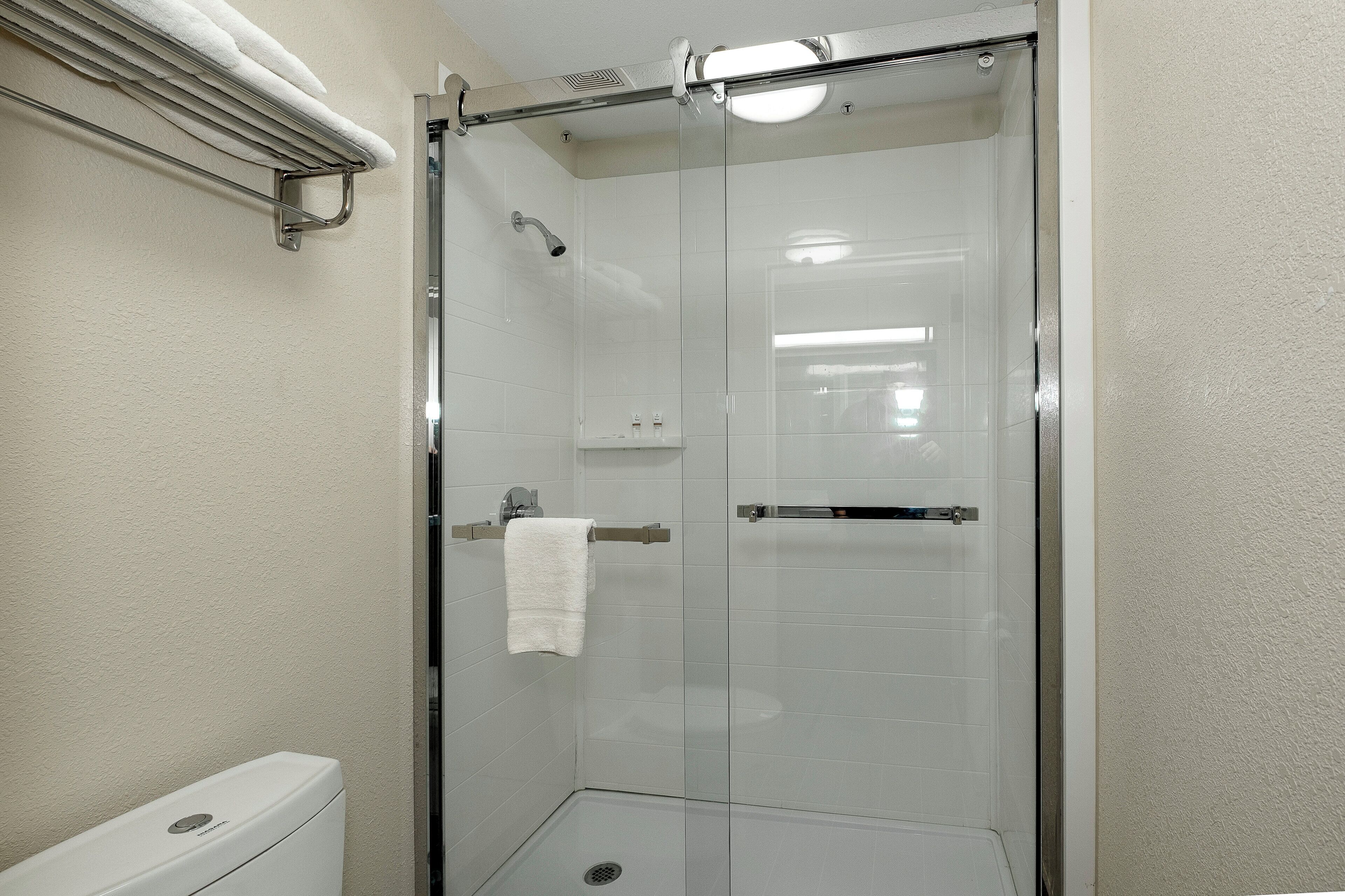 Eine begehbare Dusche mit Glastrennwand und ein weißes Handtuch am Türgriff.