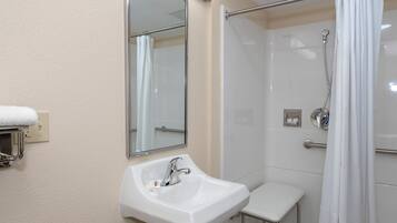 Un baño con un lavabo blanco, un espejo, una ducha con puerta de cristal y un perchero para toallas.