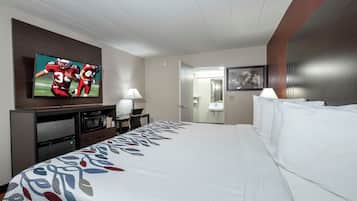 Habitación de hotel con una cama grande, un televisor de pantalla plana en la pared, un escritorio con lámpara, microondas y refrigerador.