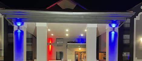 A hotel entrance with a covered outdoor area, columns, and potted plants.