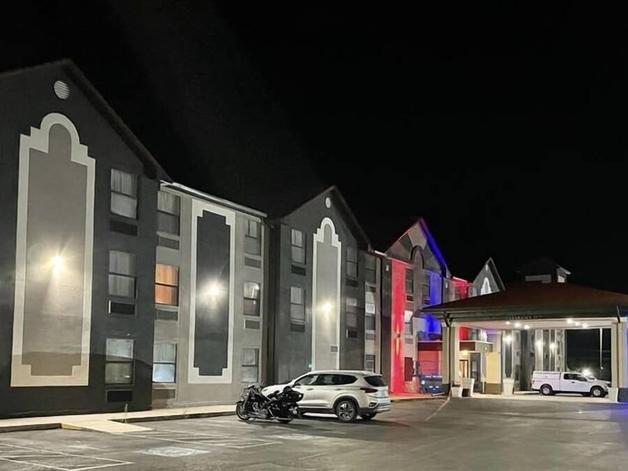 A hotel with multiple buildings, a covered entrance, and a parking area with a motorcycle and a car.