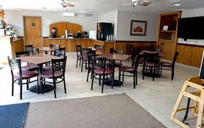 Guests can dine in comfort at this cozy space, surrounded by cushioned chairs and a mounted television.