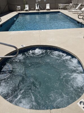 Relax by the pool with a hot tub and lounge chairs.