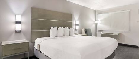 Una habitación de hotel moderna con una cama grande, una mesita de noche y una lámpara de pared.