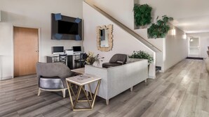 Een moderne woonkamer met een bank, stoelen, een bijzettafeltje, een televisie en een trap.