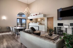 Una sala de estar moderna con un sofá, una mesa de centro y un comedor. Hay una cocina con una encimera y un televisor grande montado en la pared.