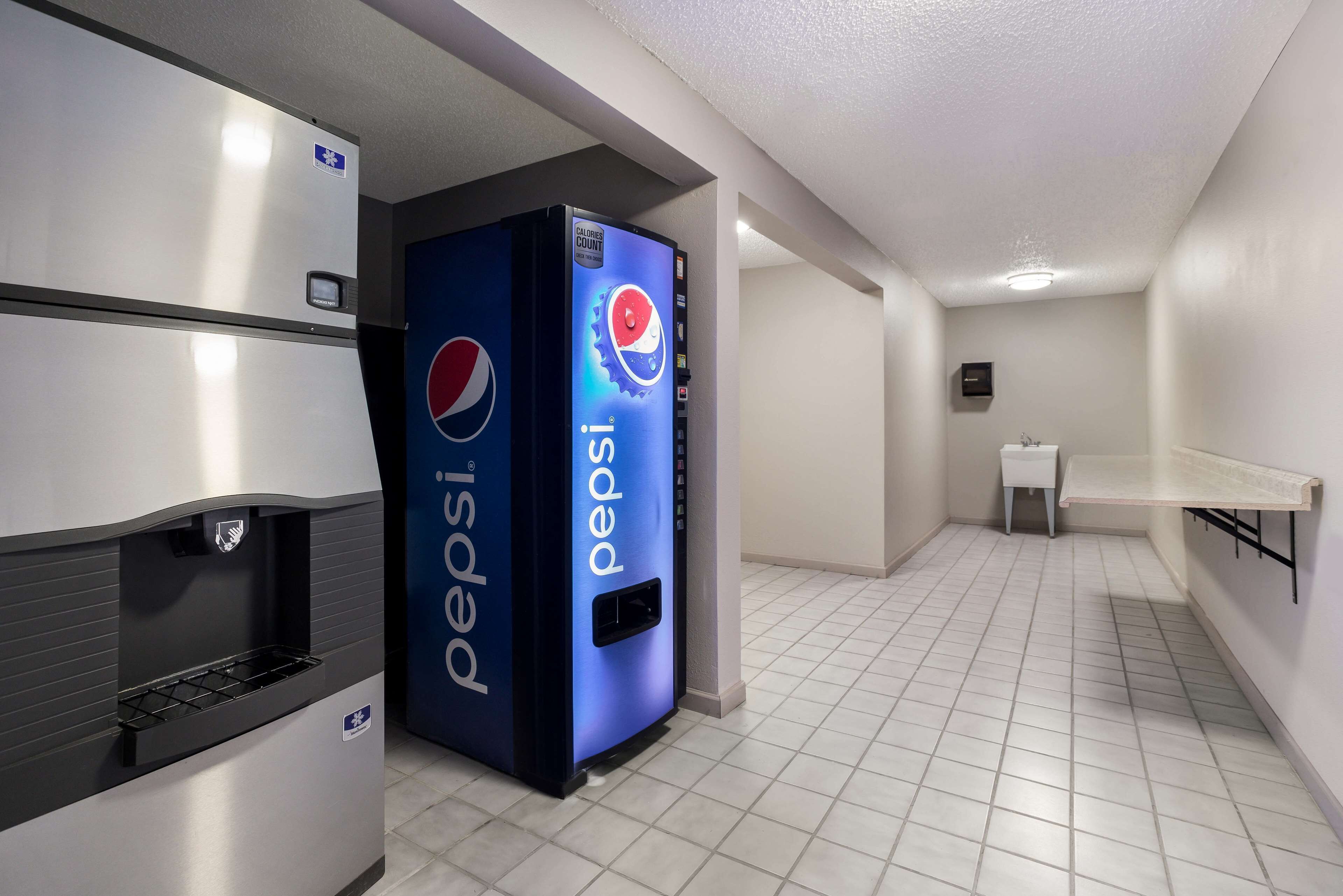 A vending machine area with a Pepsi dispenser and a refrigerator.