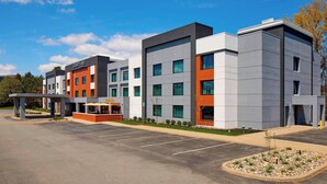 A multi-story hotel with a modern design, featuring a parking lot and a covered entrance area. - Courtyard by Marriott Albany Thruway (Albany)