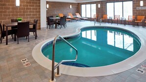 An indoor swimming pool with a tiled floor, lounge chairs, and a dining area with tables and chairs. - Courtyard by Marriott Albany Thruway (Albany)