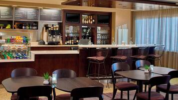 A hotel bar with multiple seating areas, a variety of beverages, and a menu board.