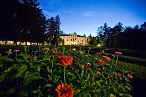 A large, illuminated building with a formal garden in the foreground. - Geneva On The Lake (Geneva)
