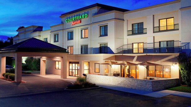 Un hôtel Courtyard Marriott doté d’une entrée couverte, d’un espace extérieur aménagé et de plusieurs balcons.