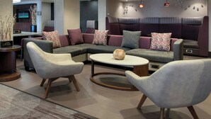Un salon moderne comprenant un canapé d’angle, deux fauteuils, une table basse et un téléviseur.
