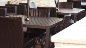 Un espace extérieur aménagé en terrasse, avec des meubles en osier et un mur en pierre.