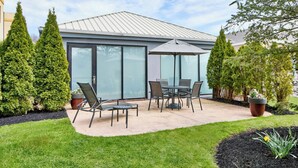 A patio area with a table and chairs, surrounded by potted plants and a well-maintained lawn. - Fairfield Inn by Marriott Rochester East (Webster)