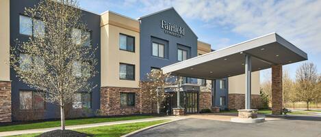 A Fairfield by Marriott hotel with a modern design, featuring a covered entrance and a landscaped area with a tree.
