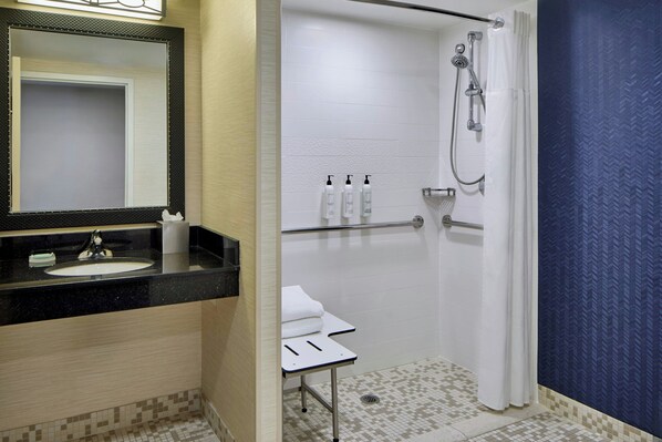 Une salle de bain équipée d’un lavabo, d’un miroir, d’une douche et d’articles de toilette.