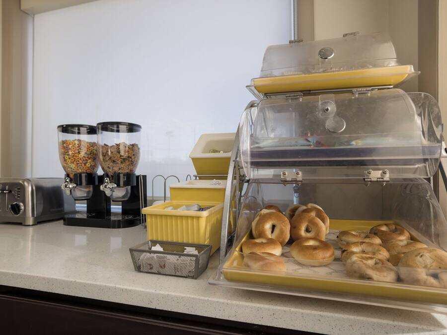 A breakfast station with a toaster, cereal dispensers, and a pastry display.