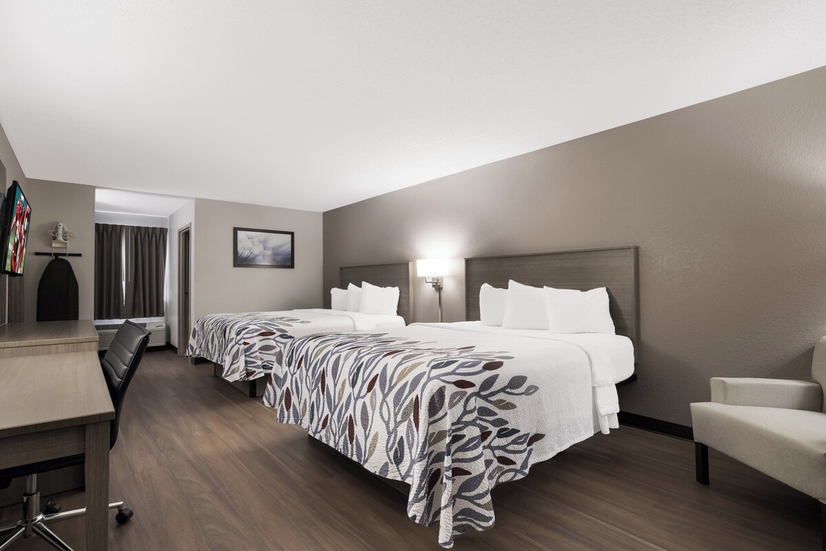 A hotel room with a large bed, a desk, and a chair.