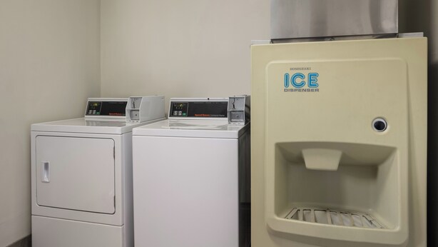 A laundry area with two front-loading washers and a water dispenser. - Red Roof Inn Weedsport (Weedsport)