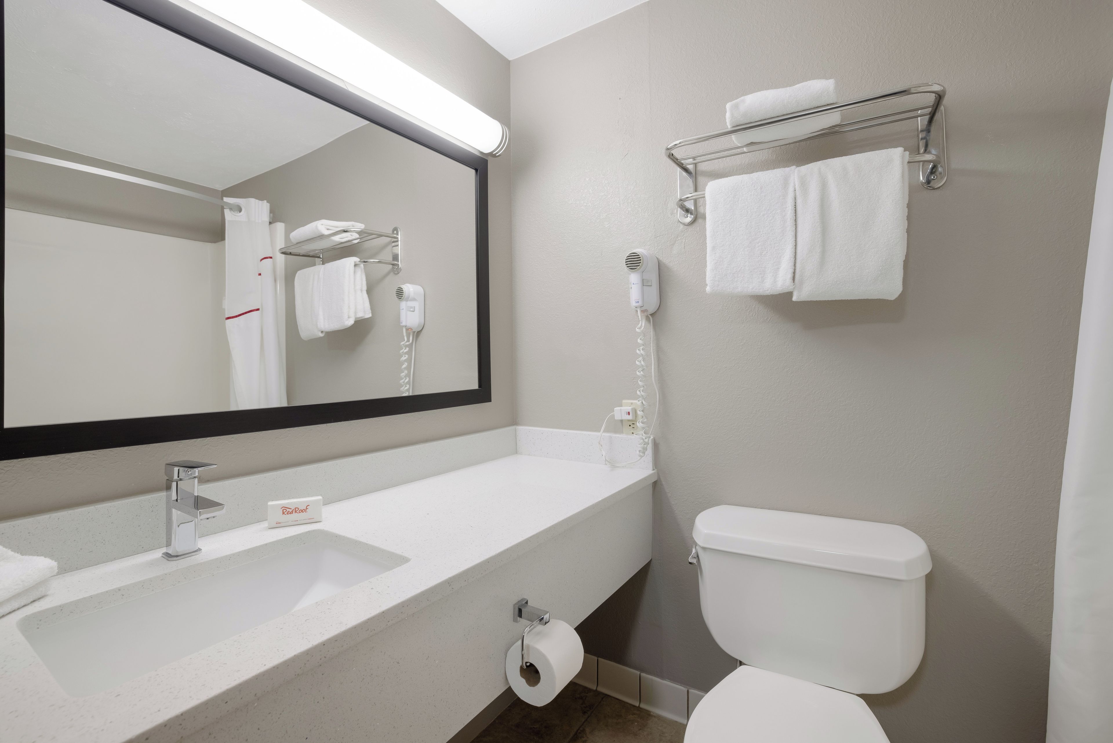 Un bagno con un lavandino bianco, un water, un porta asciugamani e un asciugacapelli.