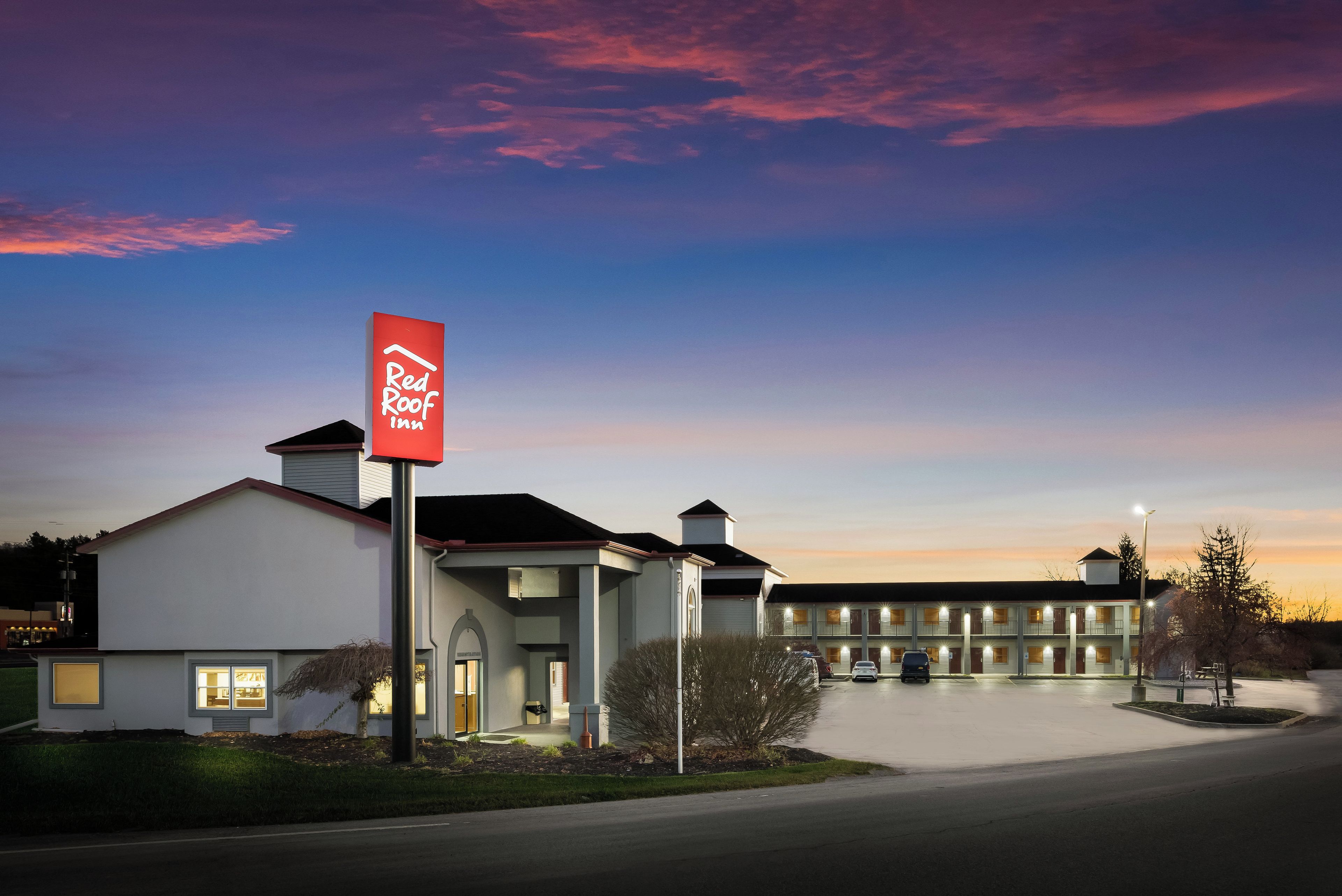 Suuri Red Roof Inn -kyltti, parkkipaikka ja useita kerroksia sisältävä rakennus.