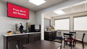 A hotel room with a kitchenette, a dining area, and a large window.