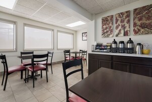 Cocina limpia y moderna con comedor, que incluye una estación de café con diferentes cafeteras y un refrigerador.