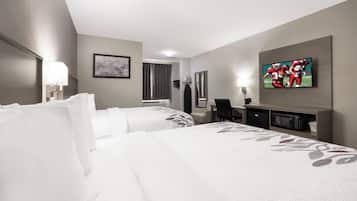 Ein Hotelzimmer mit zwei Betten, einem Flachbildfernseher, einem Schreibtisch und einem Spiegel.