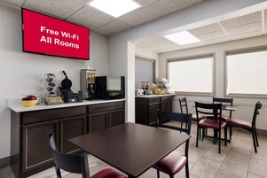 A hotel room with a kitchenette, a dining area, and a large window.