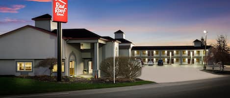 A Red Roof Inn with a modern design, a well-lit entrance, and a parking area.