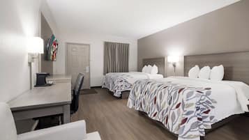 Une chambre d’hôtel avec deux lits, un bureau, une chaise et un téléviseur.