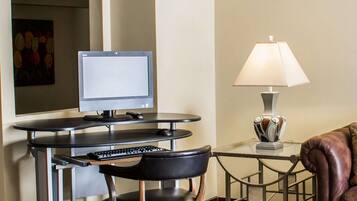 Una habitación moderna con escritorio, computadora, teclado, silla, lámpara y un sofá de cuero.