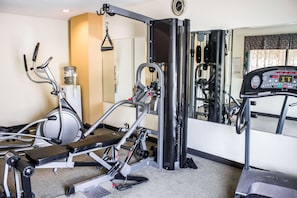 Academia com máquinas de cardio, equipamentos de musculação e espelho.