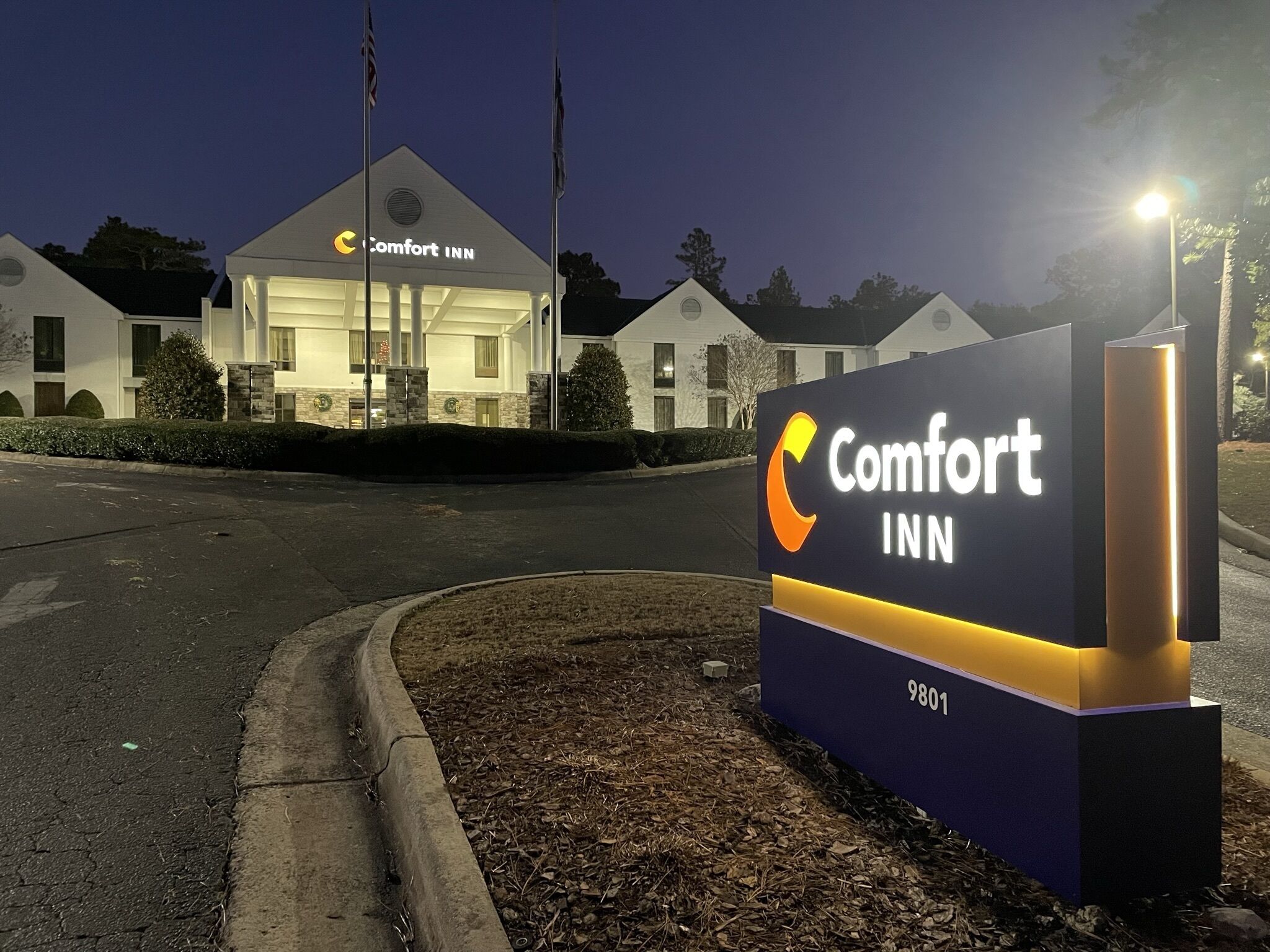 Une enseigne « Comfort Inn » au design moderne, située devant un bâtiment de style architectural traditionnel.