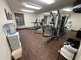 A gym with various exercise equipment, a water dispenser, and a large water cooler.