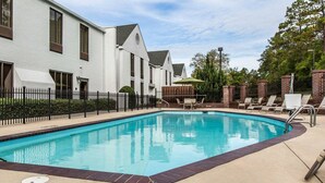 A rectangular swimming pool with a tiled edge, surrounded by a brick and metal fence.