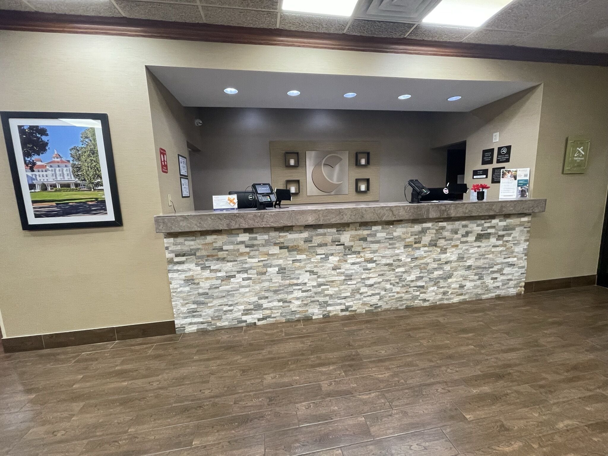 A reception desk with a stone facade, a framed picture on the wall, and a clock.