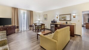 Quarto de hotel com sala de estar, mesa de jantar, cozinha e televisão.