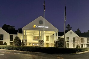 A Comfort Inn hotel with a prominent sign, a flagpole, and a well-lit entrance.