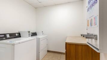 A laundry room with a washing machine, dryer, and a bulletin board with bleach softeners.