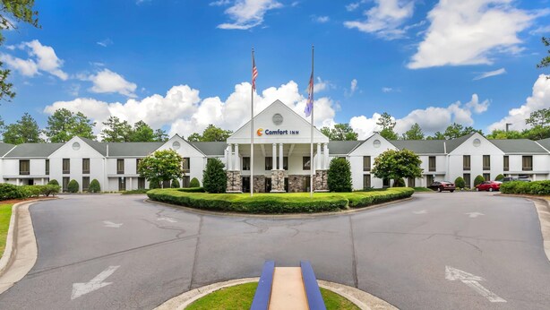 A Comfort Inn hotel with a symmetrical facade, two flagpoles, and a central entrance.